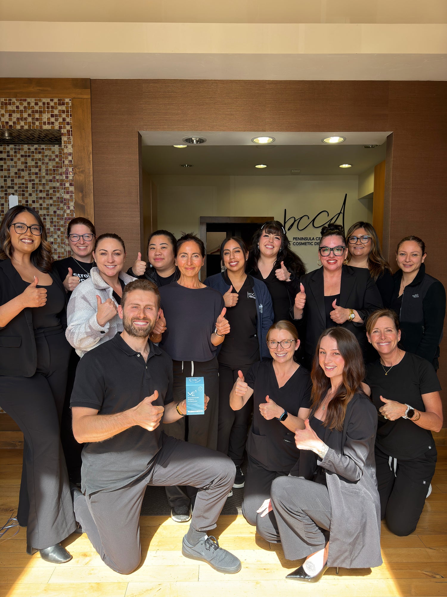 Group of people posing together with thumbs up in a professional setting